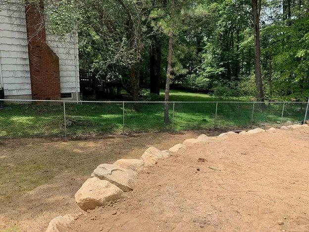 A house with a fence and a pile of dirt in front of it.