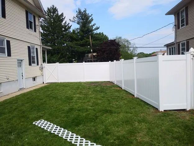 A white fence is in the backyard of a house