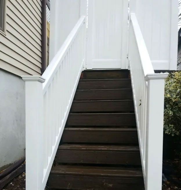A set of stairs leading up to a house with a white railing