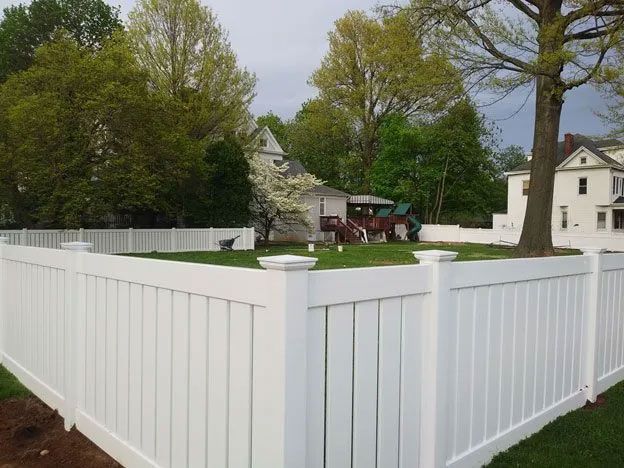 A white fence surrounds a lush green yard