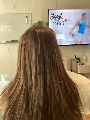 Woman seen from behind watching a TV in a salon with “Body Sculpting Levels” on screen
