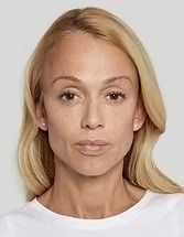 Portrait of a blonde person with a neutral expression, wearing a white shirt against a gray background