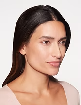 Close-up portrait of a person with dark hair against a light background, looking to the side with a slight smile.