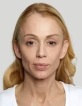 Portrait of a blonde woman against a plain gray background, facing forward with a neutral expression