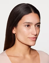 Portrait of a person with long dark hair on a light background, facing slightly right with a neutral expression