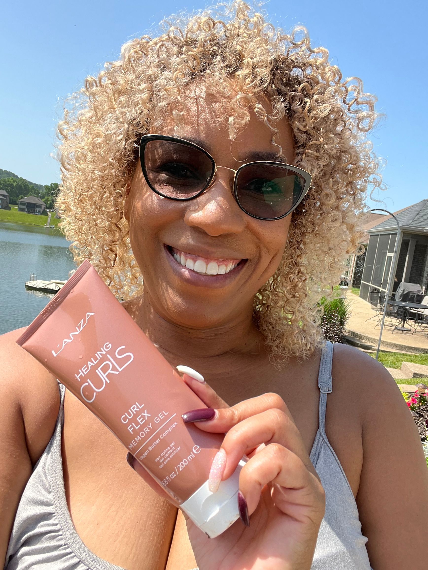 A woman with curly hair is holding a bottle of lotion.