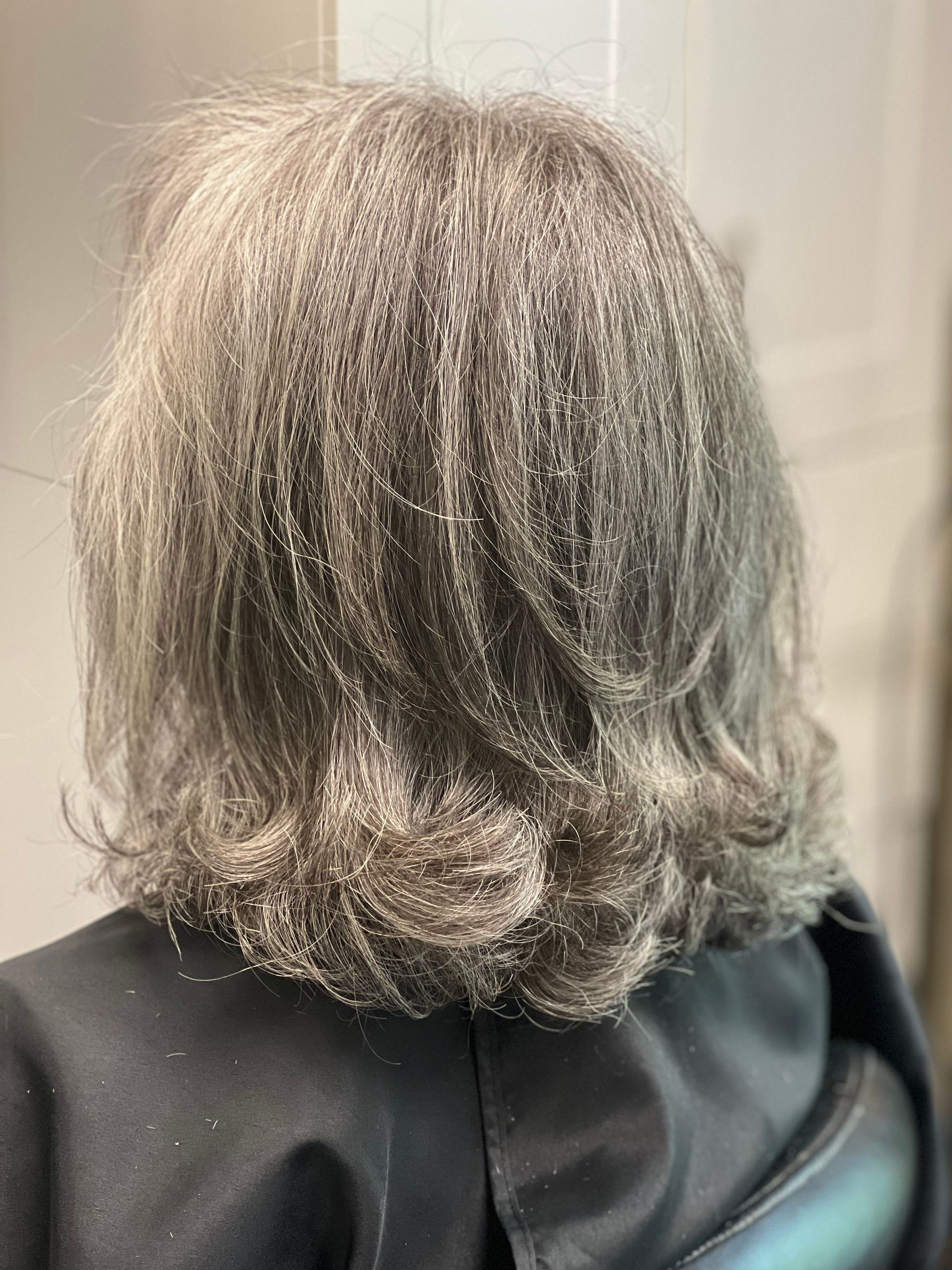 A woman with gray hair is sitting in a chair.