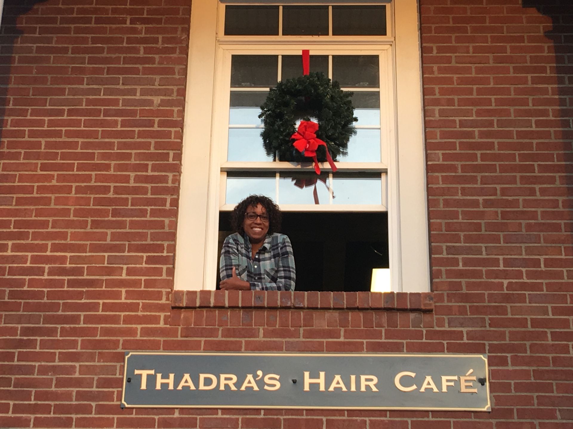 A woman looks out a window at thadra 's hair cafe