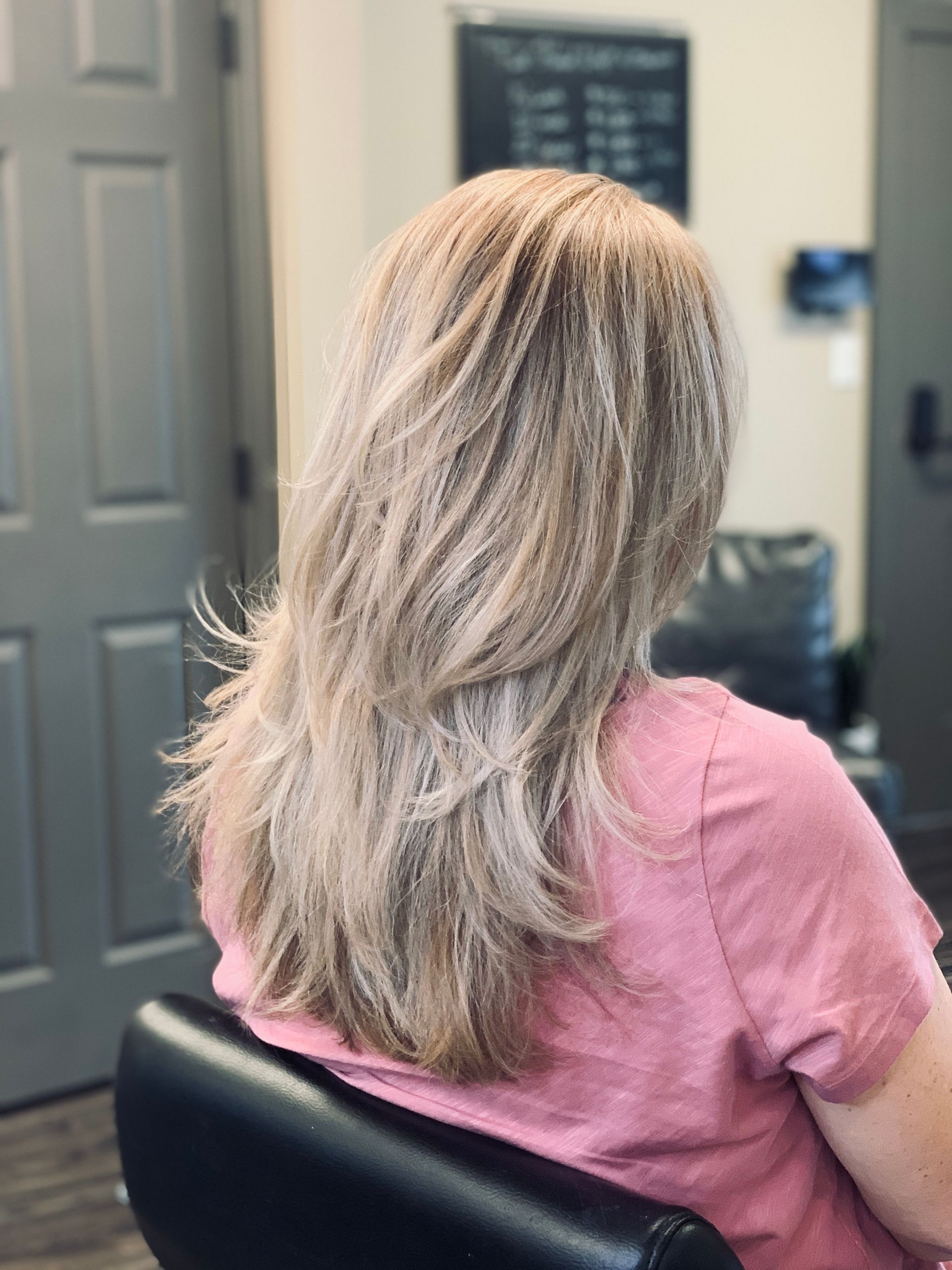 A woman is sitting in a chair with her hair blowing in the wind.