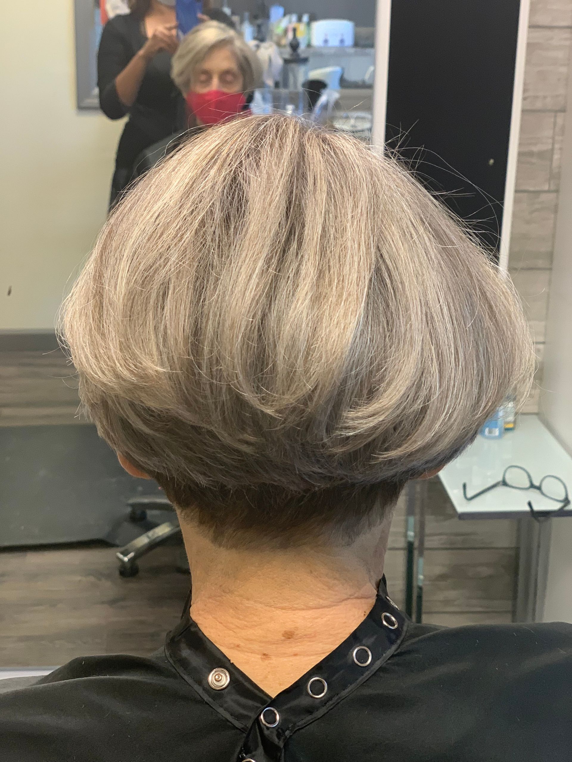 A woman is getting her hair cut in a salon.