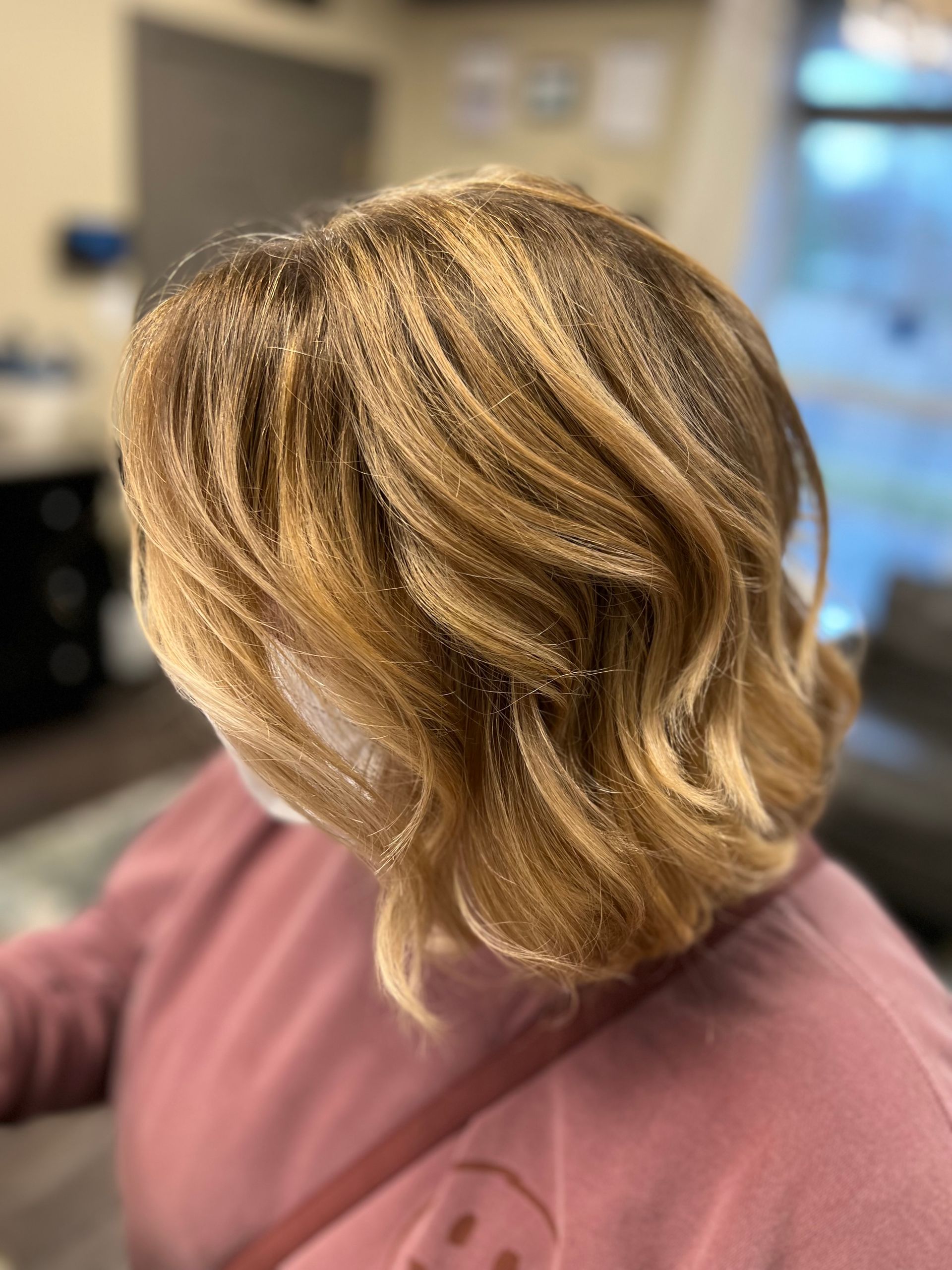 A woman with short blonde hair is wearing a pink sweater.