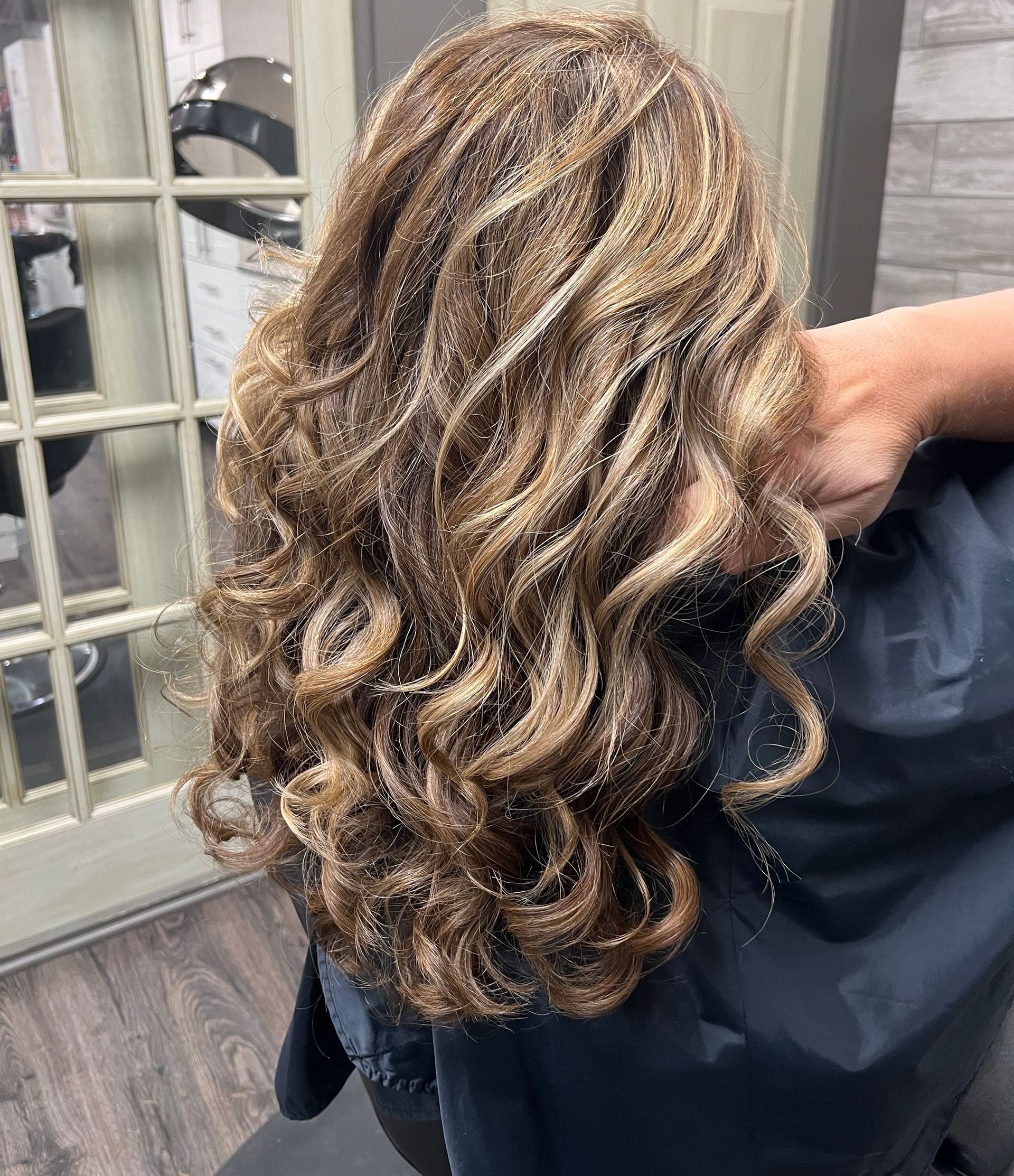 A woman is sitting in a chair with her hair in a salon.