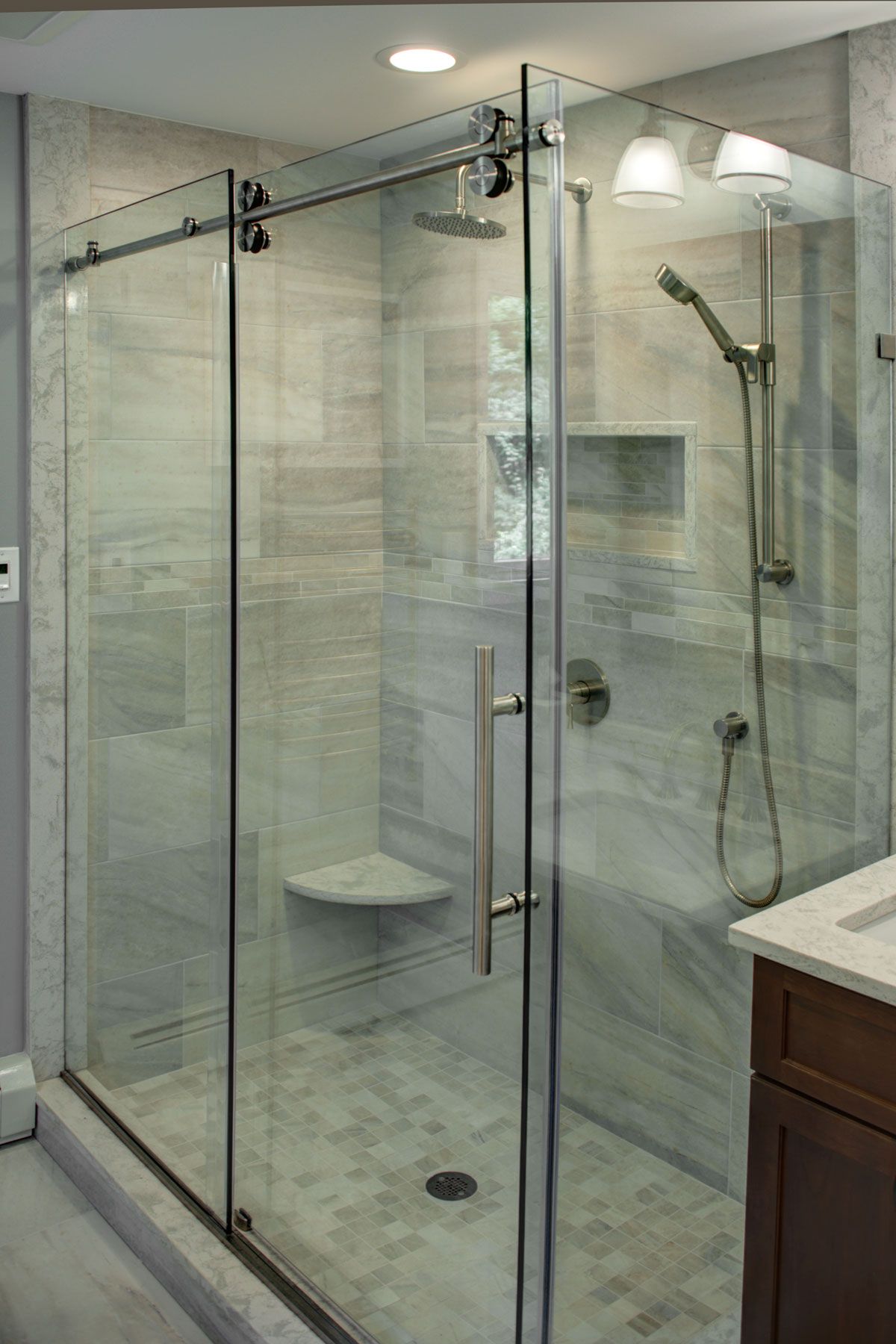 Glass shower enclosure in a bathroom with marble-look tiles and chrome fixtures