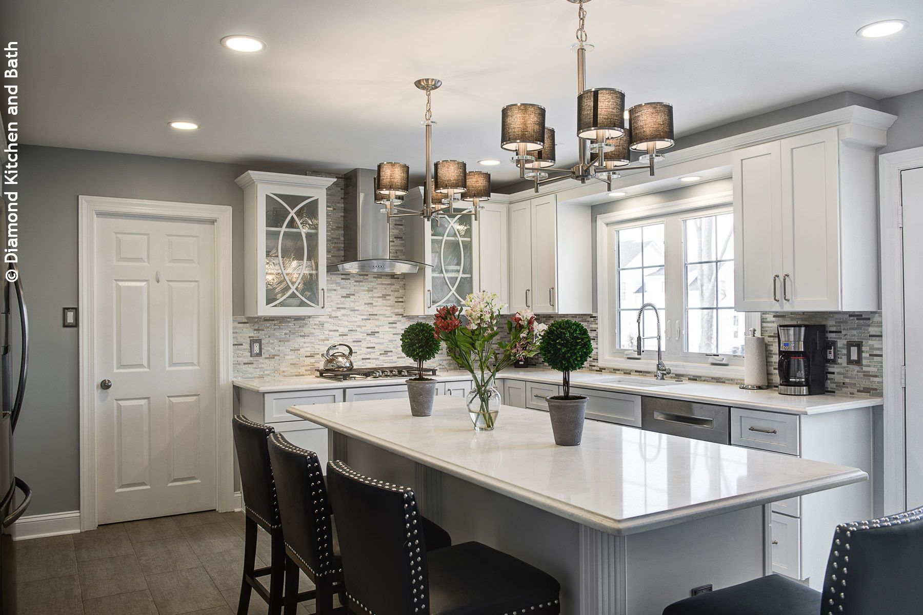 Modern white kitchen with island, pendant lights, and bar stools