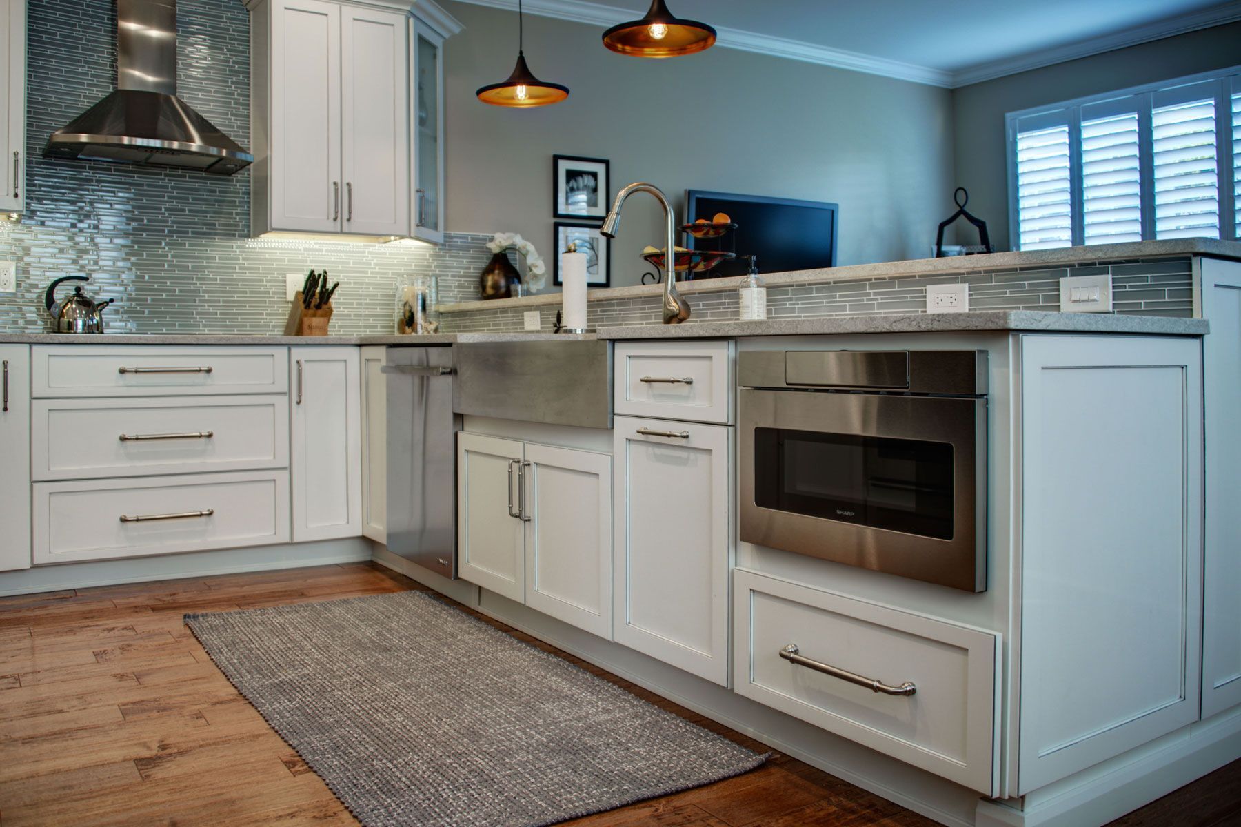 Modern white kitchen with stainless steel appliances, sink, and metallic backsplash