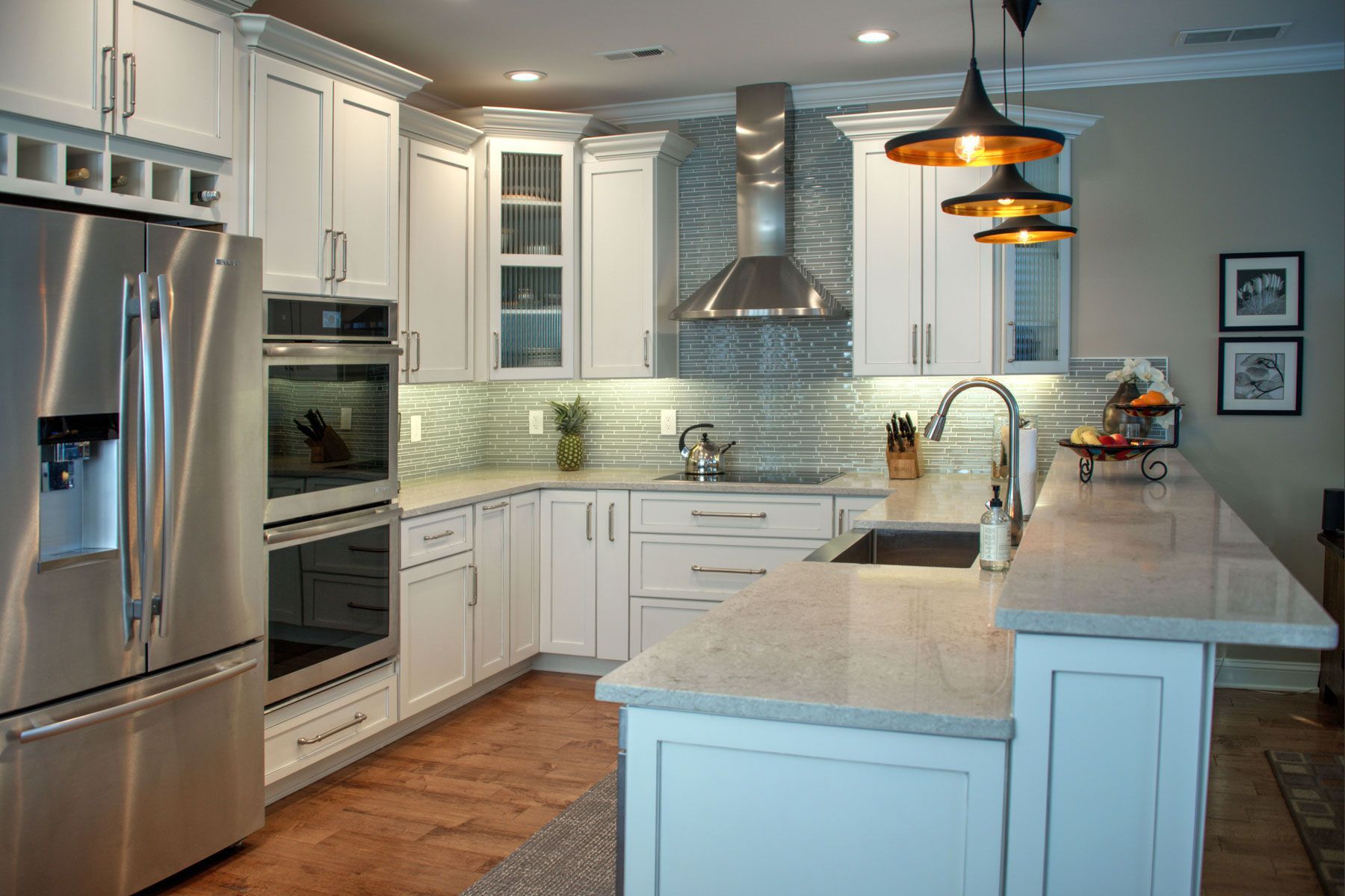 Modern white kitchen with stainless steel appliances, granite countertops, and decorative lighting