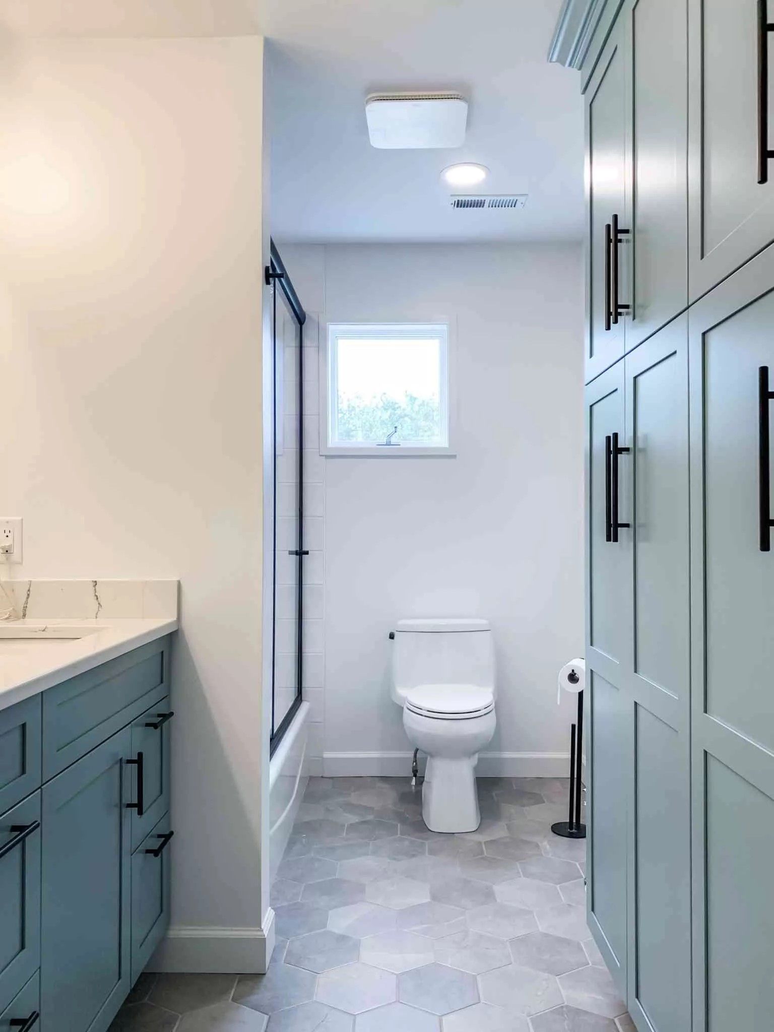 Bathroom with blue cabinets, white walls, and hexagon floor tiles