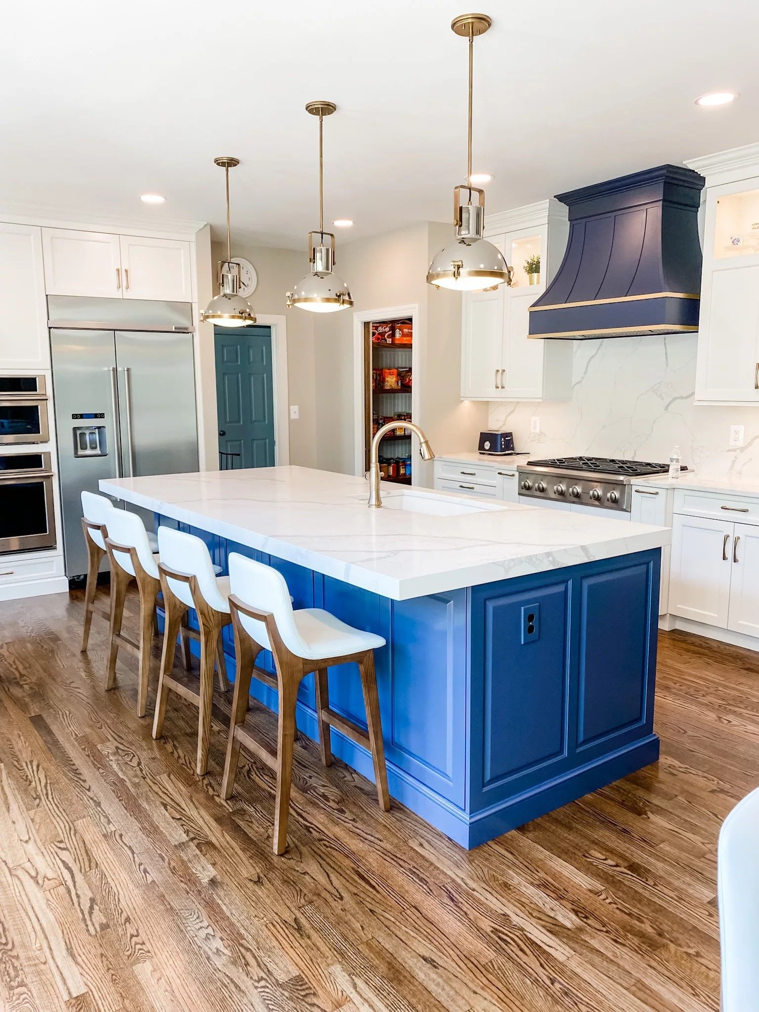 Modern kitchen with blue island, white countertops, stainless steel appliances, and wood floors