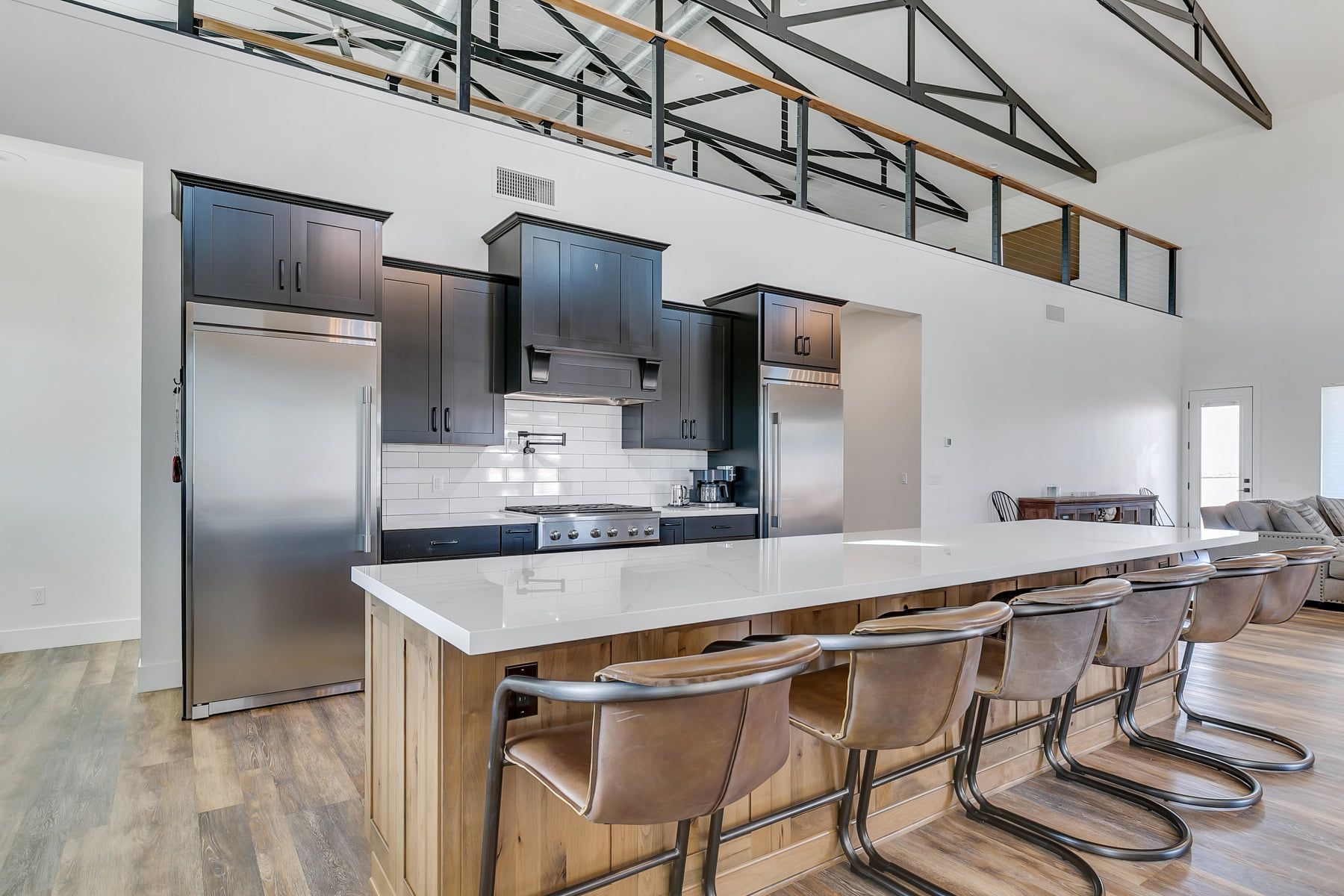 Modern kitchen with stainless steel appliances, large island with seating, and loft