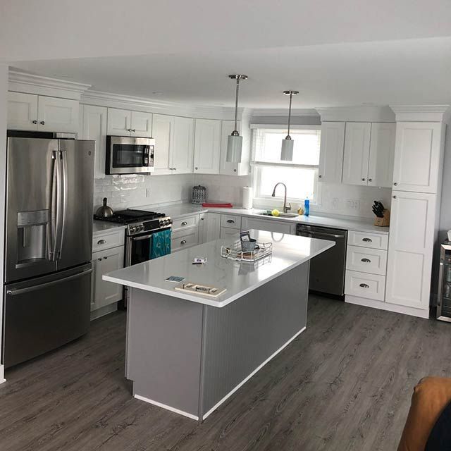 White kitchen with gray island and stainless steel appliances; light gray flooring