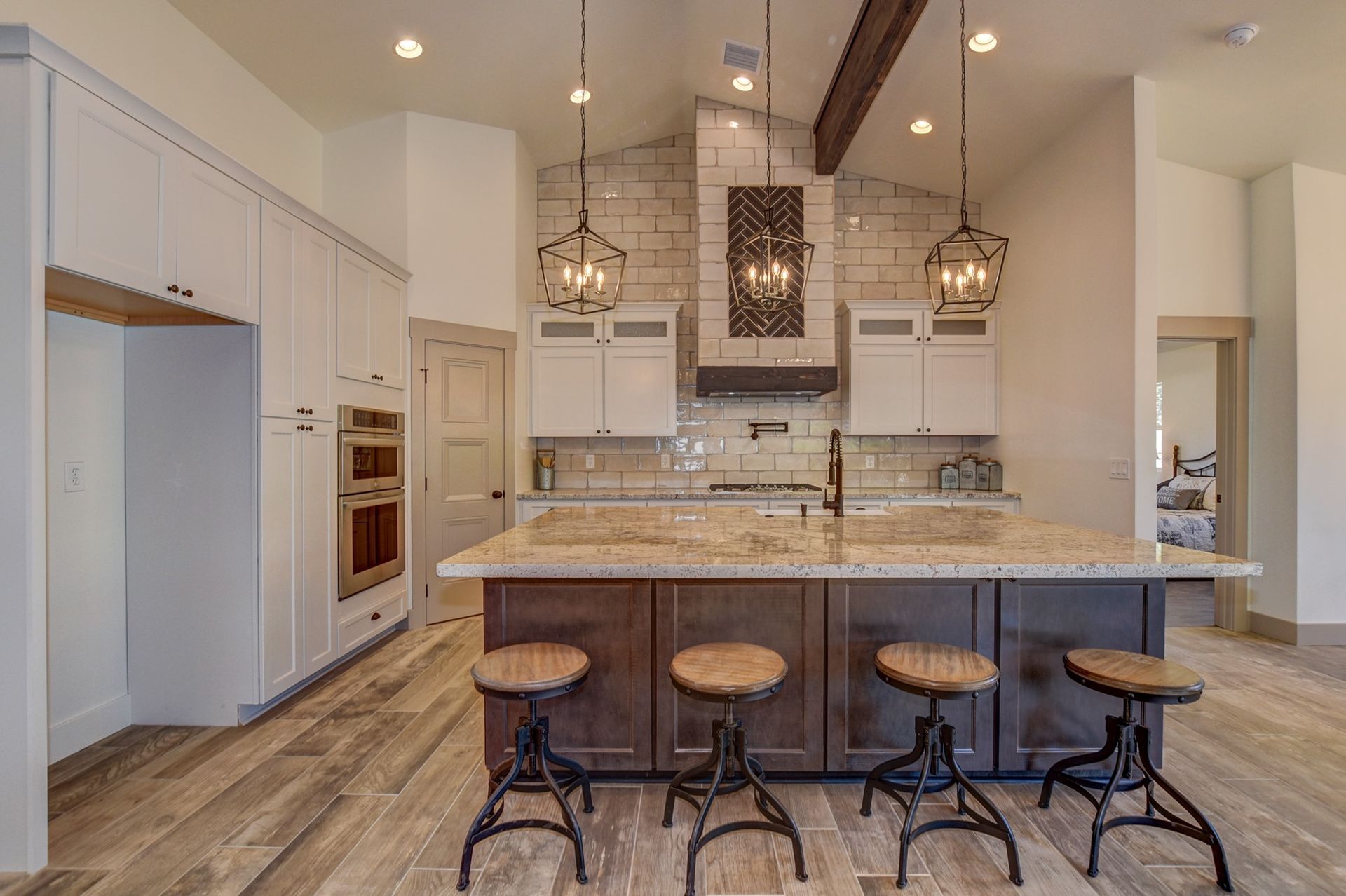 Kitchen with white cabinets, dark island with stools, and pendant lights