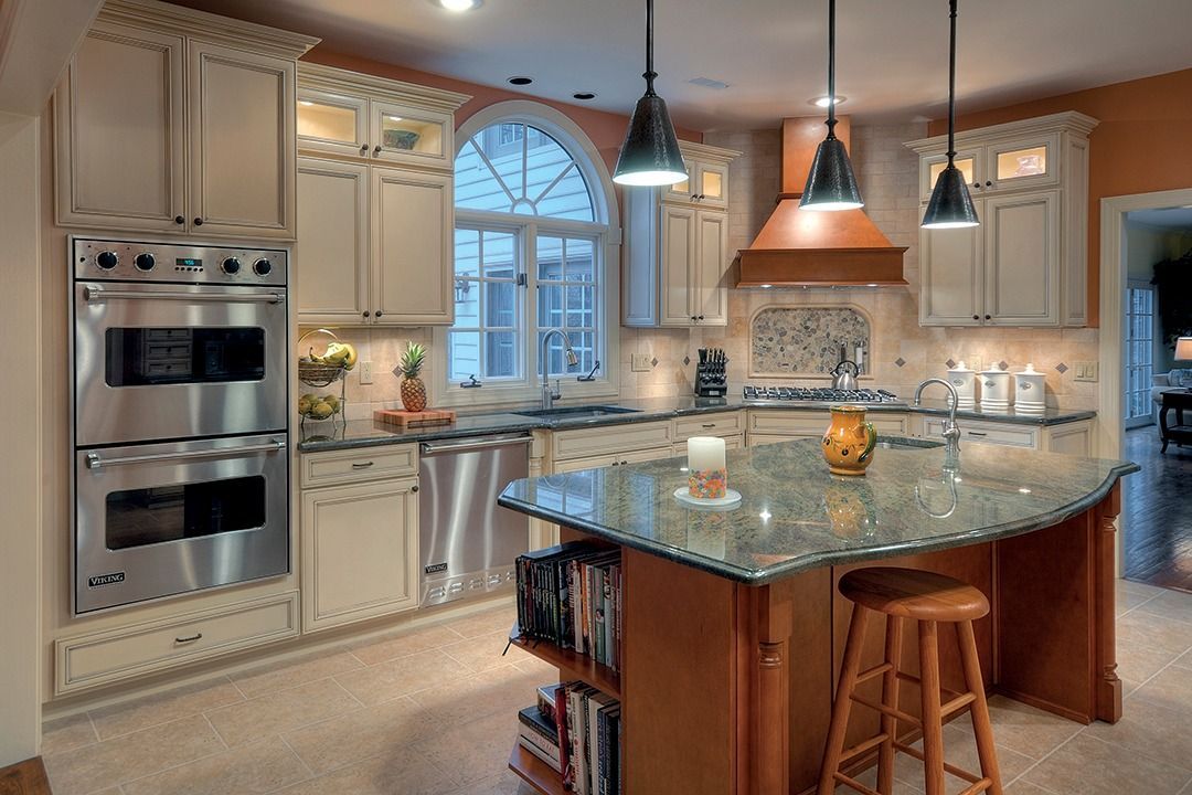 Kitchen with off-white cabinets, stainless steel appliances, and a granite island with a stool; overhead lights