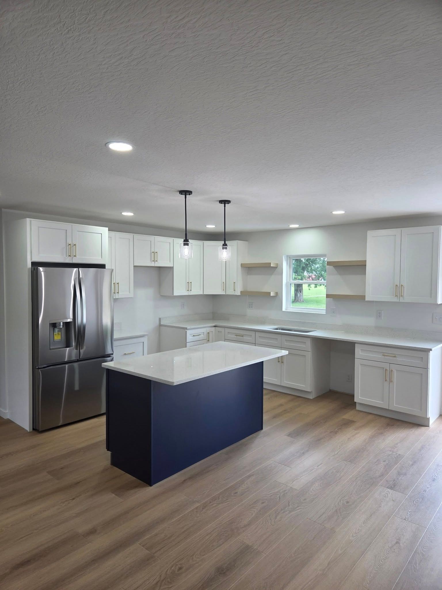 Modern white kitchen with a navy island and stainless steel refrigerator