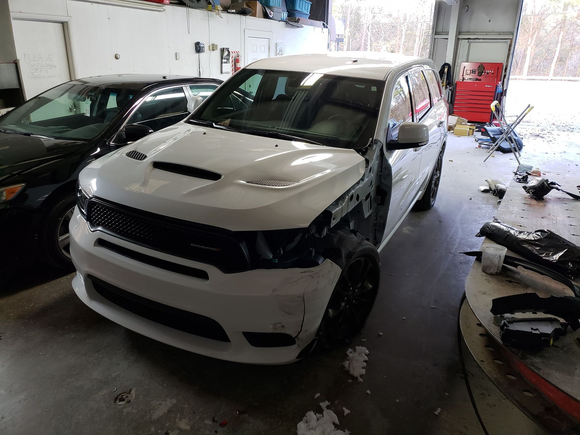 White SUV with front end damage, in a repair shop.
