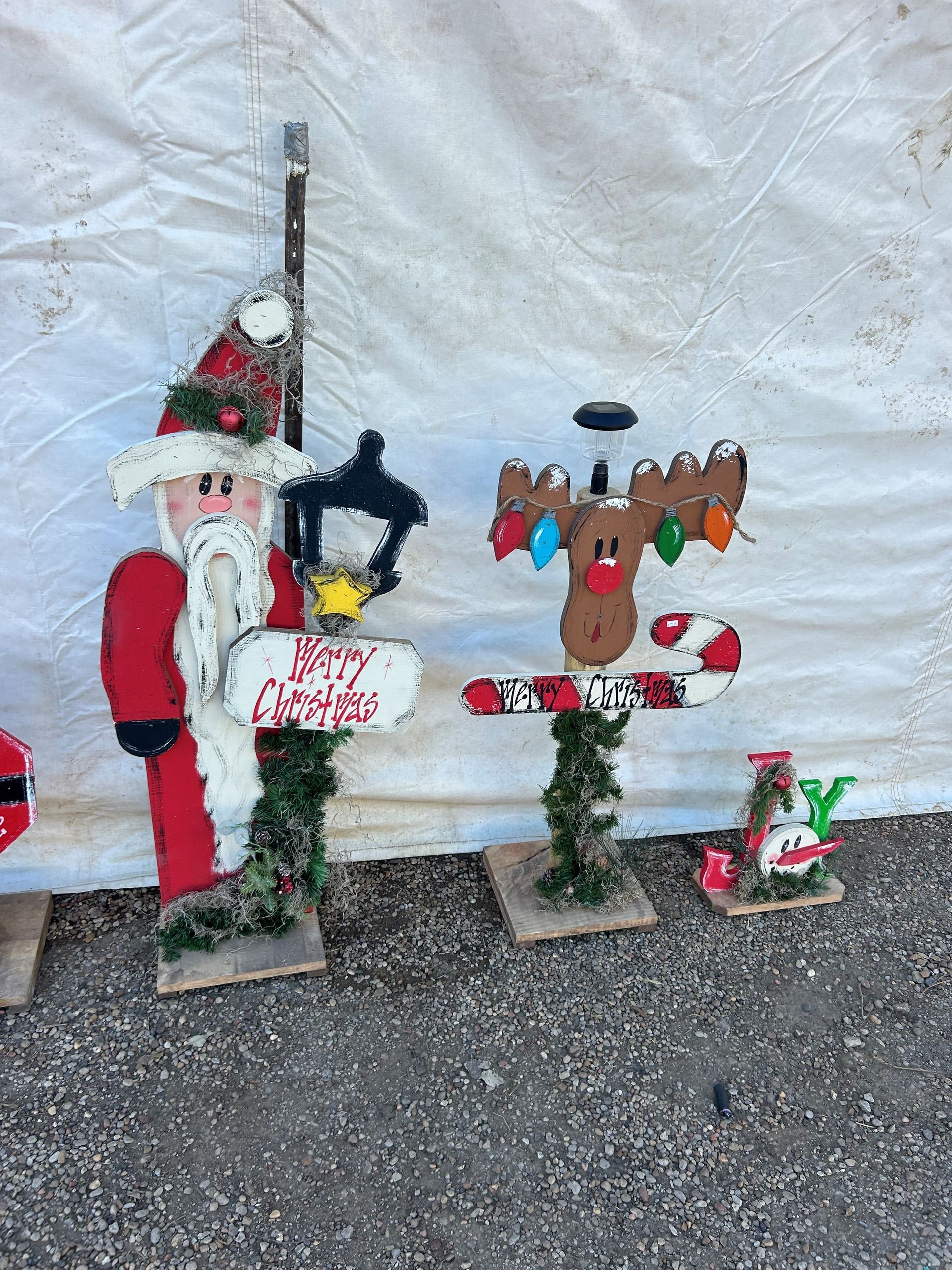 Wooden Santa and reindeer Christmas decorations with signs and lights.
