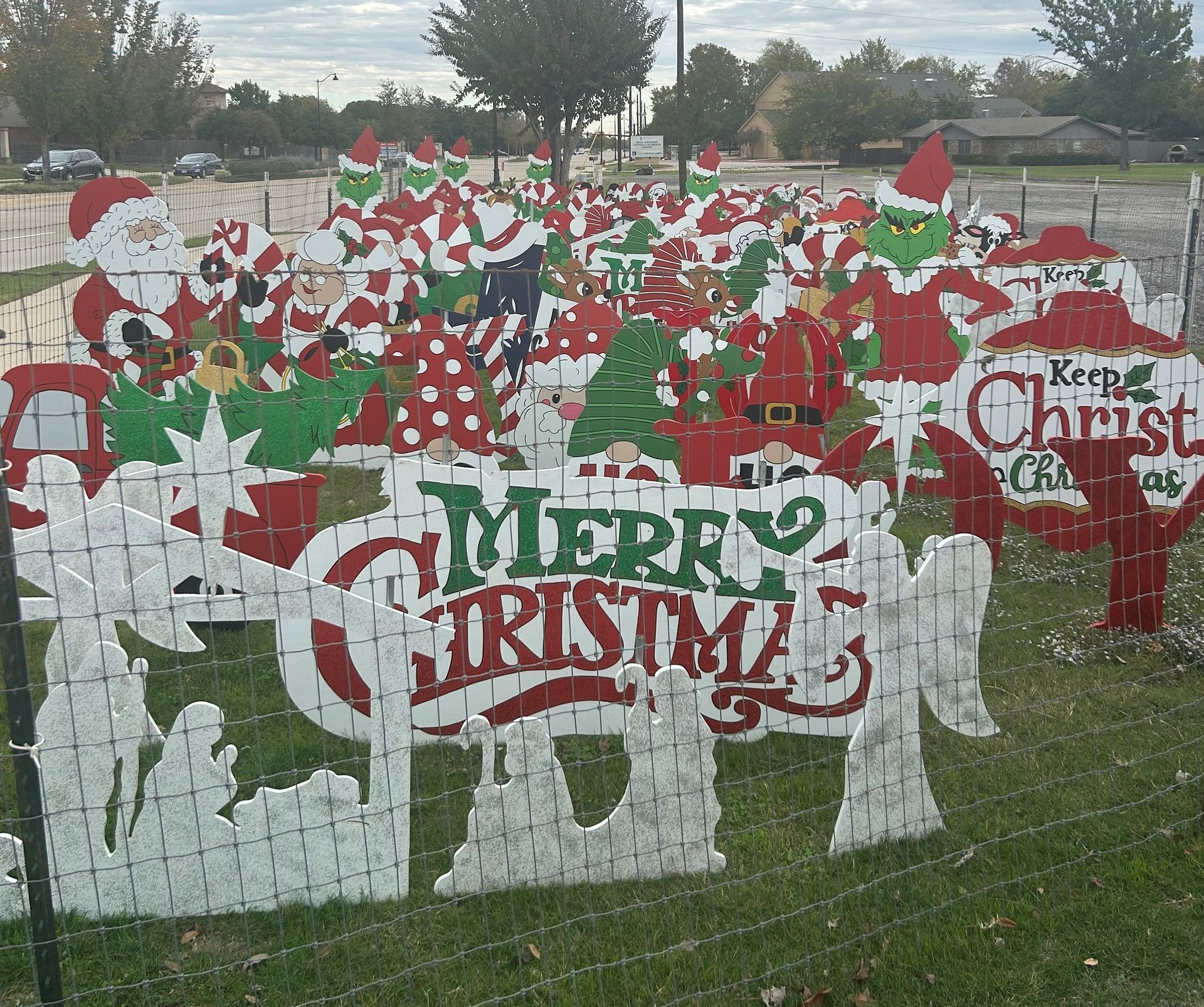 Christmas yard display featuring cut-out characters like Santa, elves, and the Grinch.