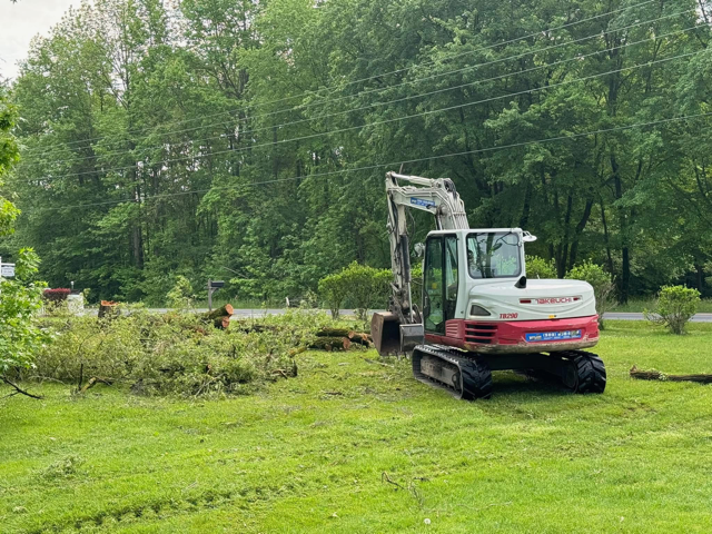 A white and red excavator is sitting in the middle of a lush green field