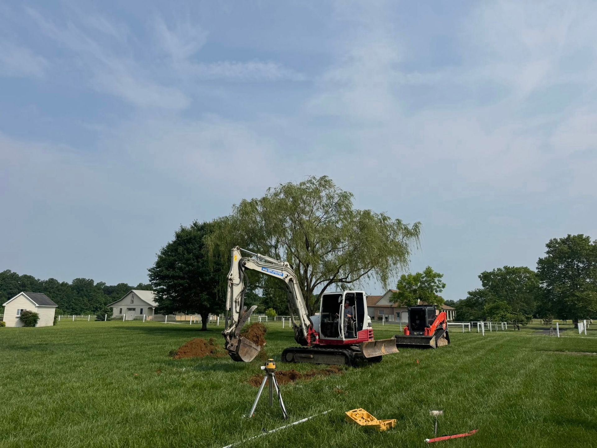 A couple of excavators are sitting in a grassy field.