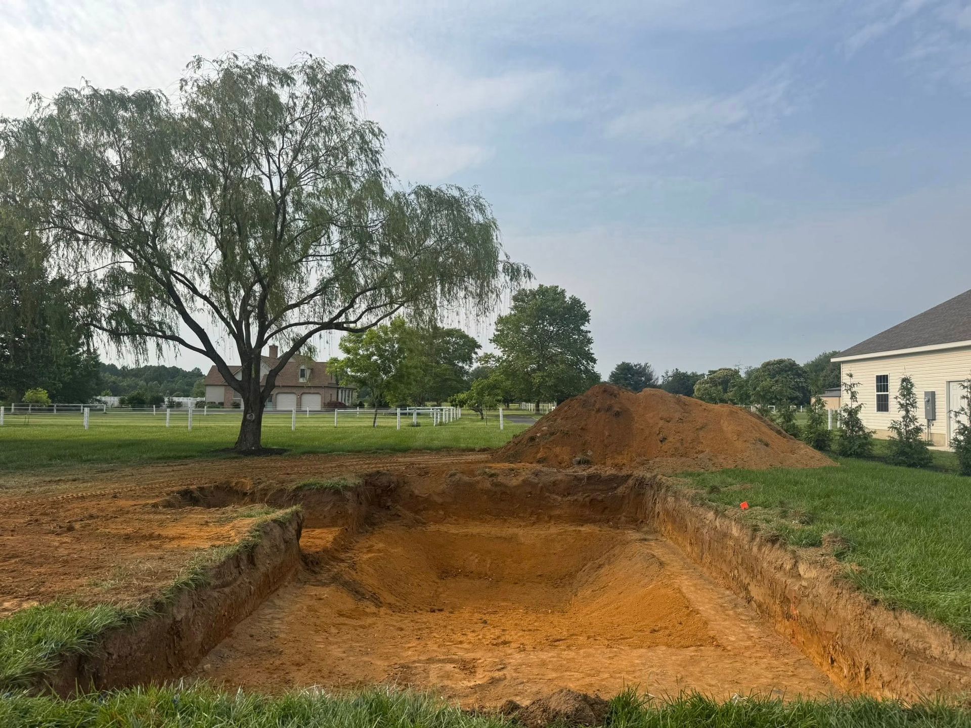 A large pile of dirt is sitting in the middle of a field next to a tree.