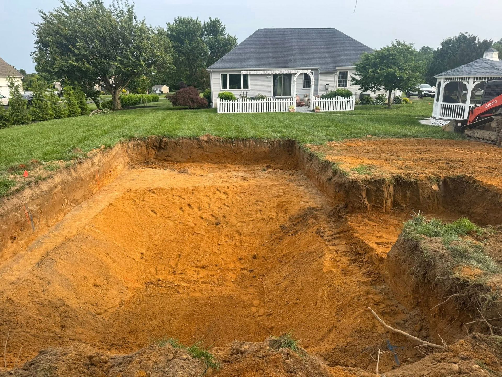 A swimming pool is being built in the backyard of a house.