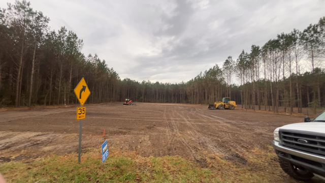 A white truck is parked in the middle of a dirt road in the middle of a forest