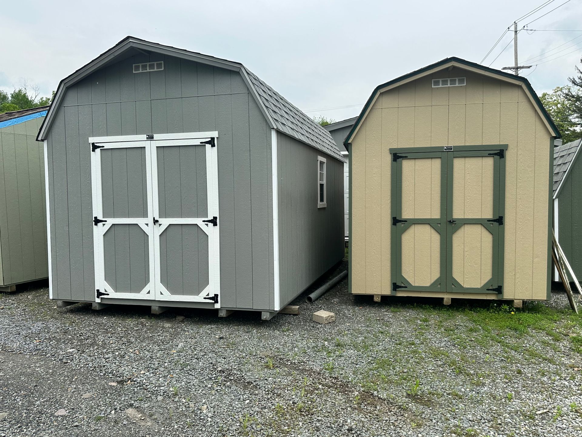 A row of sheds are lined up in a gravel lot.