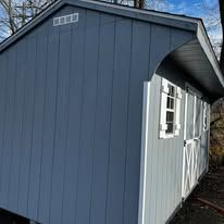 A gray barn is sitting on top of a trailer.