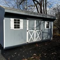 A gray barn is sitting on top of a trailer.
