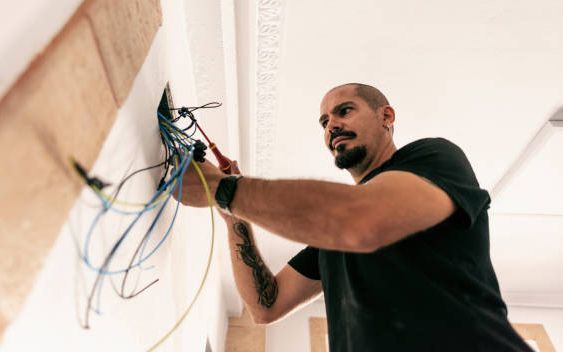 A man is working on a wall with wires.