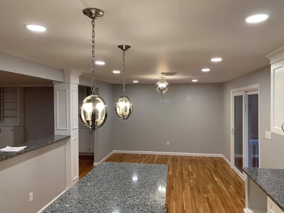 A kitchen with granite counter tops, hardwood floors, and two pendant lights hanging from the ceiling.