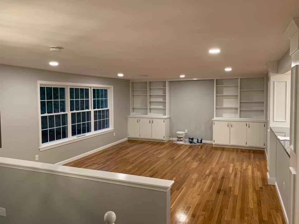 A large empty living room with hardwood floors and built in shelves.