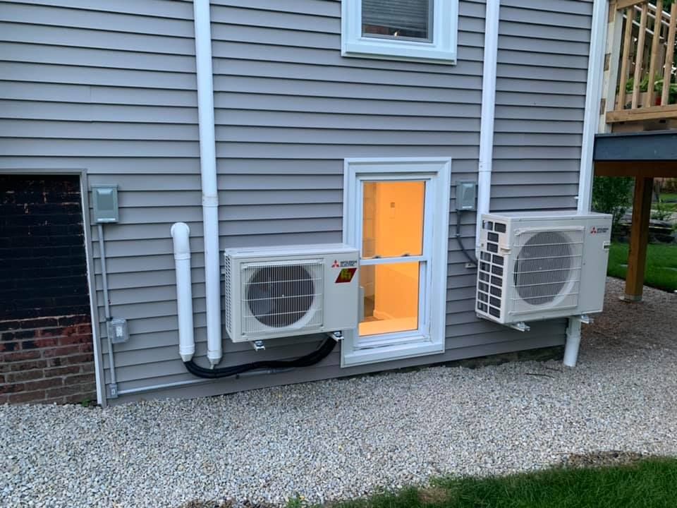 Two air conditioners are installed on the side of a house.