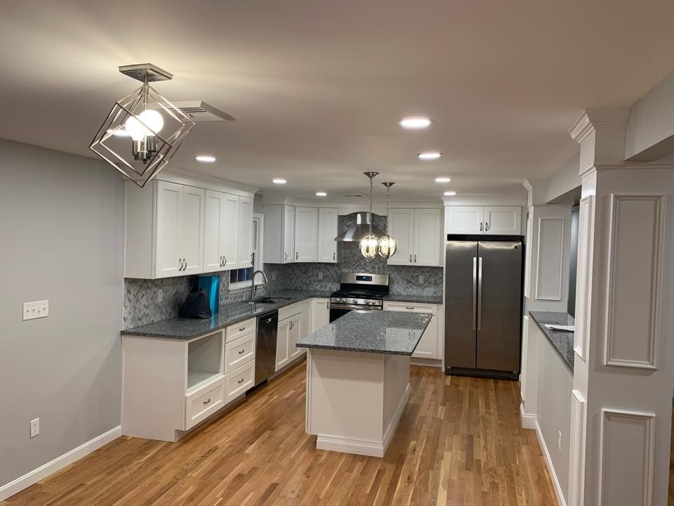 A kitchen with white cabinets, granite counter tops, stainless steel appliances, and hardwood floors.