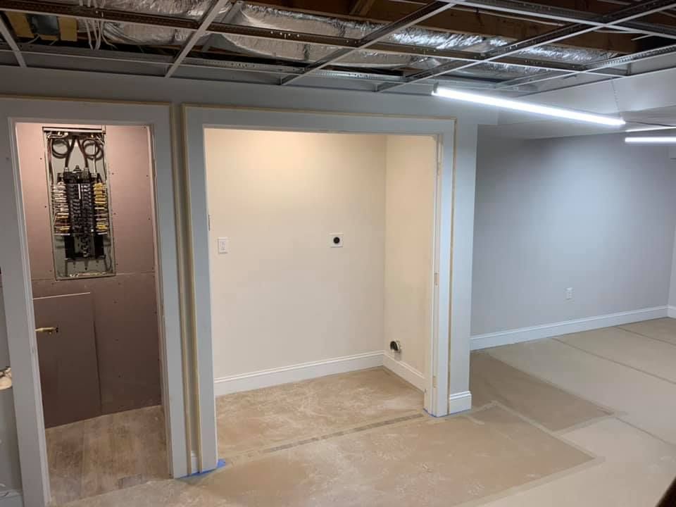 An empty basement with a doorway leading to a bathroom.