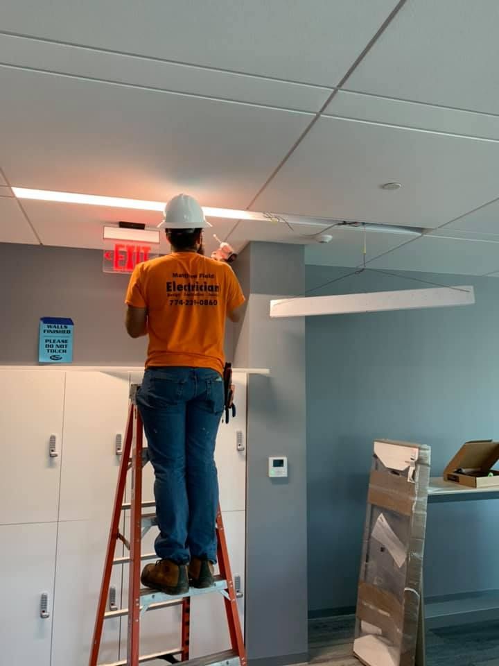A man standing on a ladder working on a ceiling.