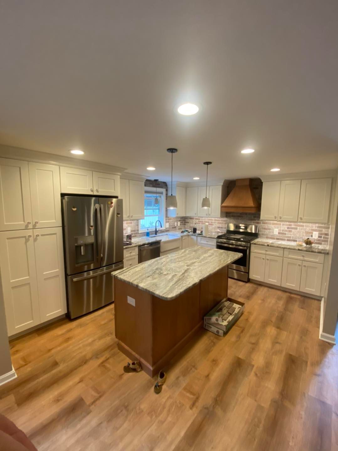 A kitchen with white cabinets, stainless steel appliances, granite counter tops, and a large island.