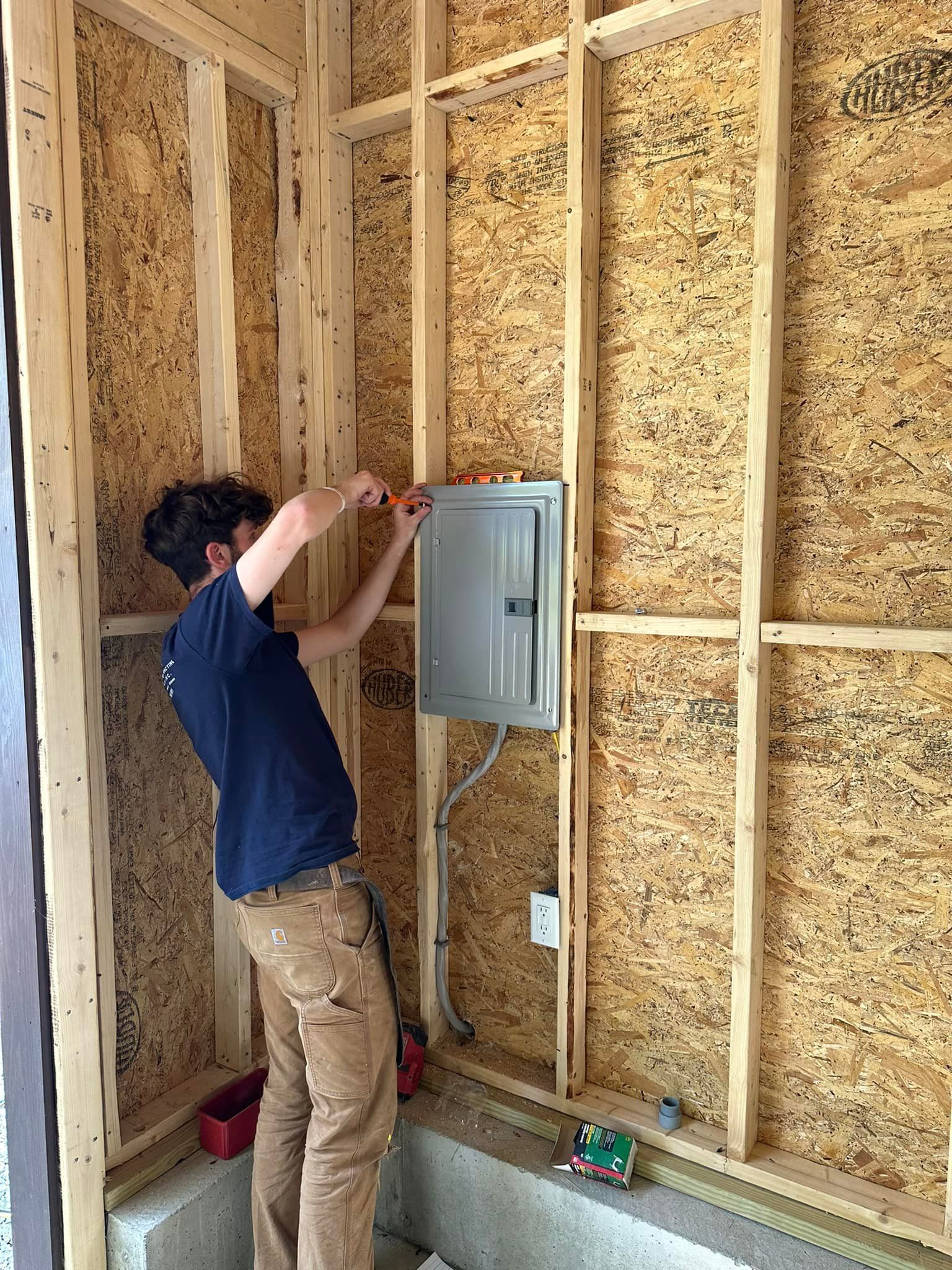 A man is working on an electrical box in a room.
