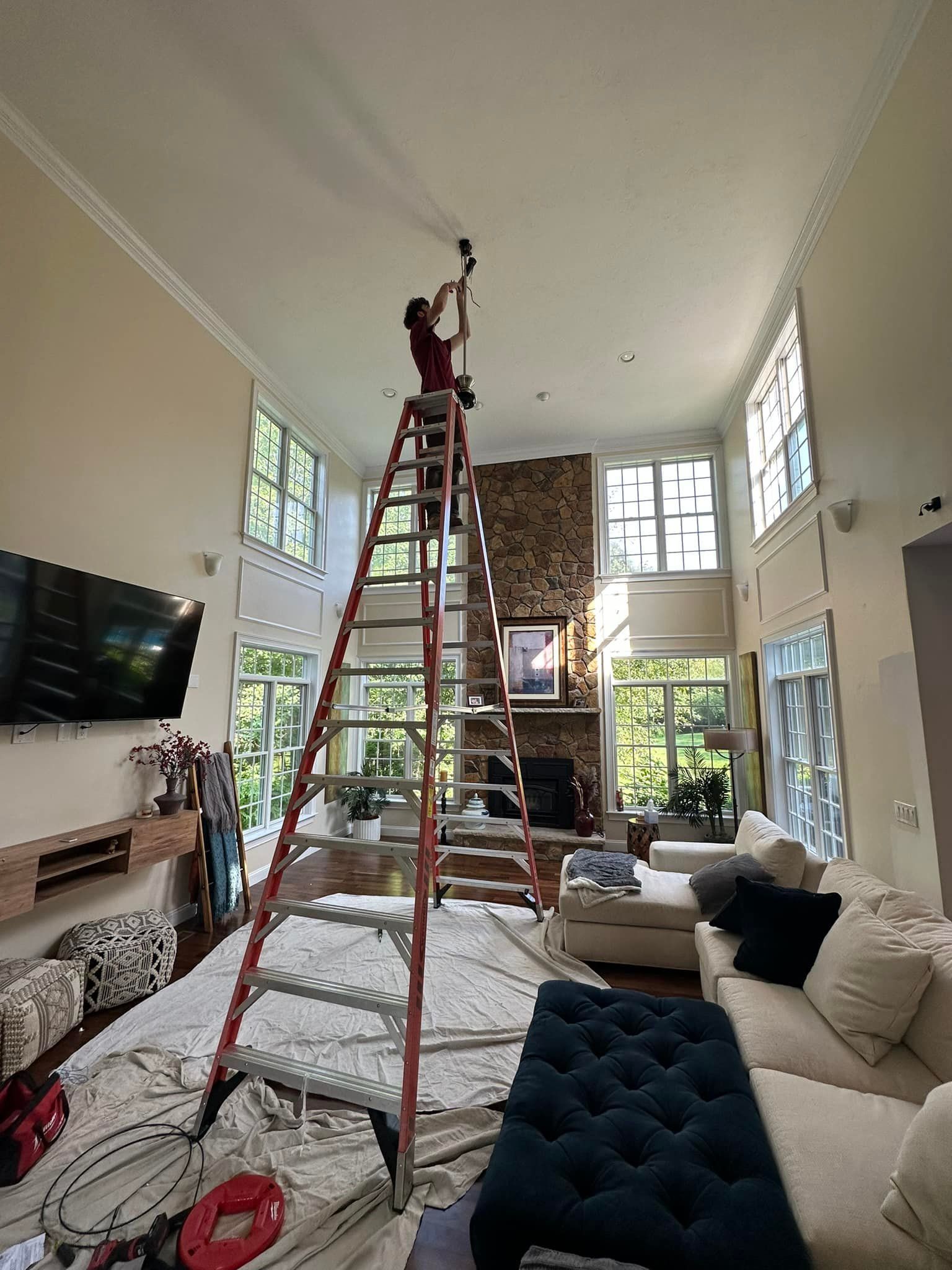 A man is standing on a ladder in a living room.