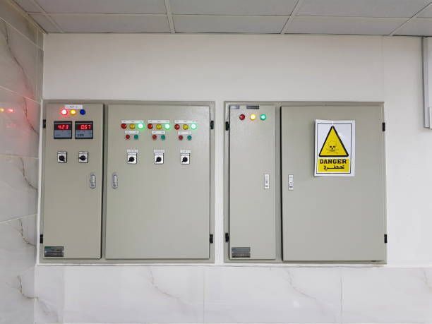 Two electrical boxes on a wall with a yellow warning sign on them.