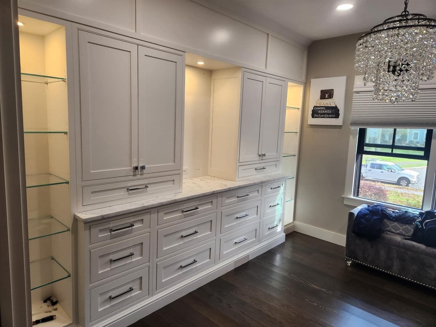 A room with a lot of cabinets and drawers and a chandelier.